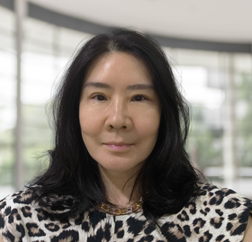 A woman wearing a leopard print shirt is smiling for the camera.