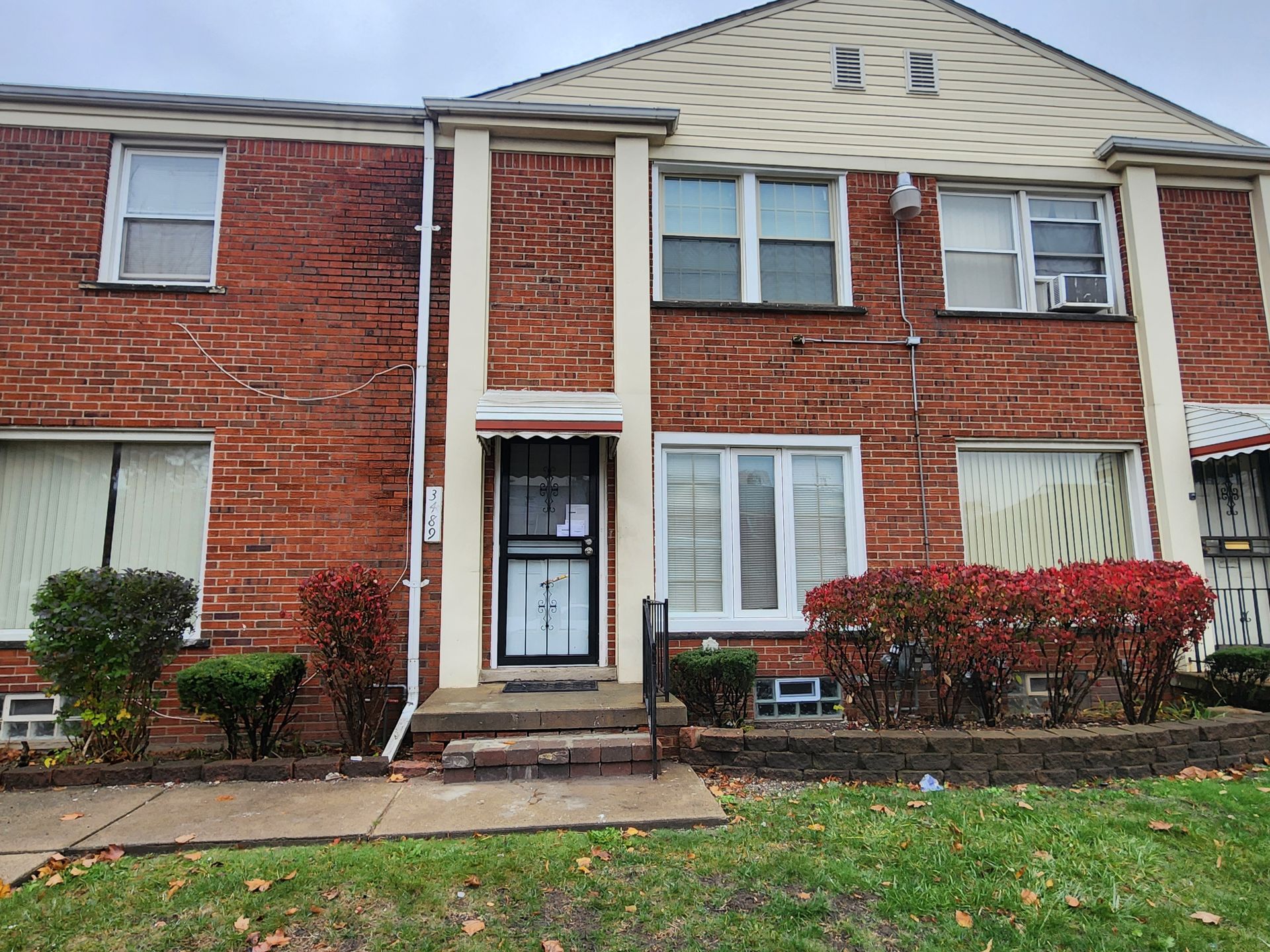 A brick apartment building with a lawn in front of it.