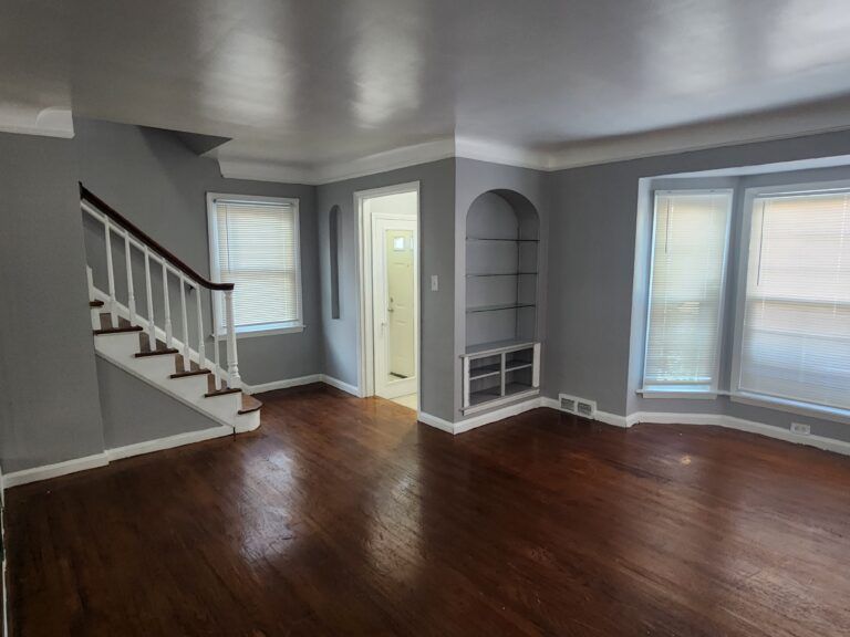 An empty living room with hardwood floors and stairs