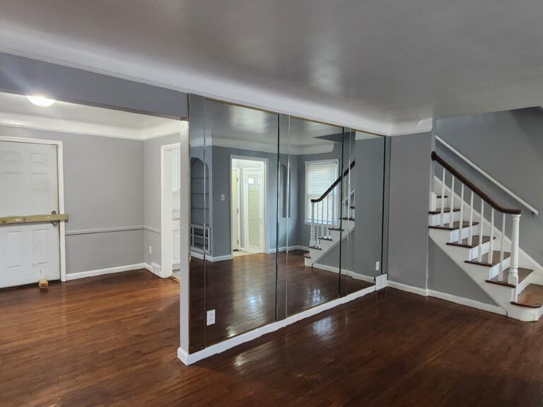 An empty room with a mirrored wall and stairs