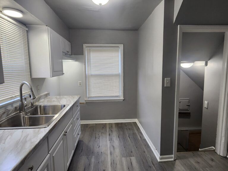A kitchen with a sink , cabinets , and a window.