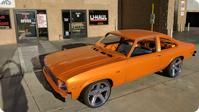 Orange car parked in front of shop | Mariposa Tire & Auto