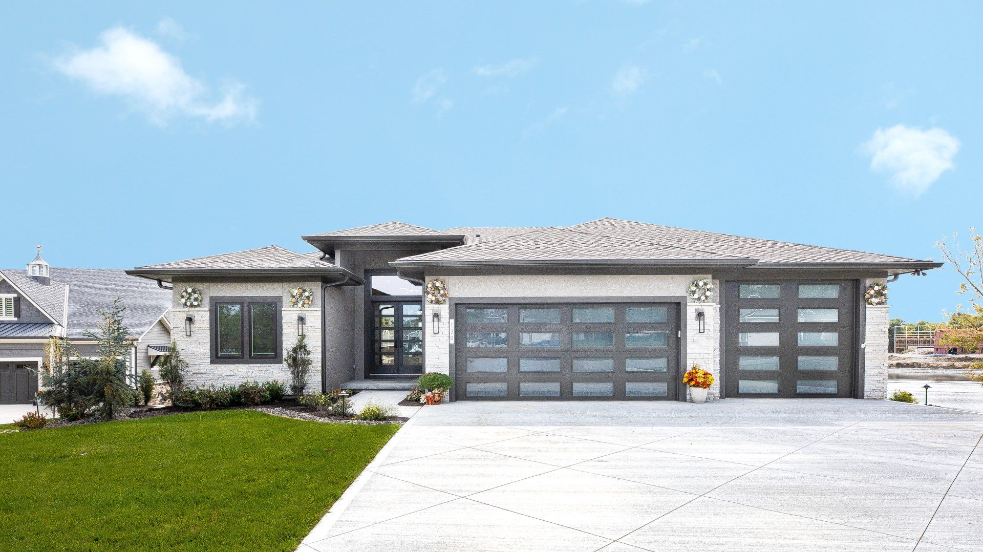 A large white house with two garage doors and a driveway.