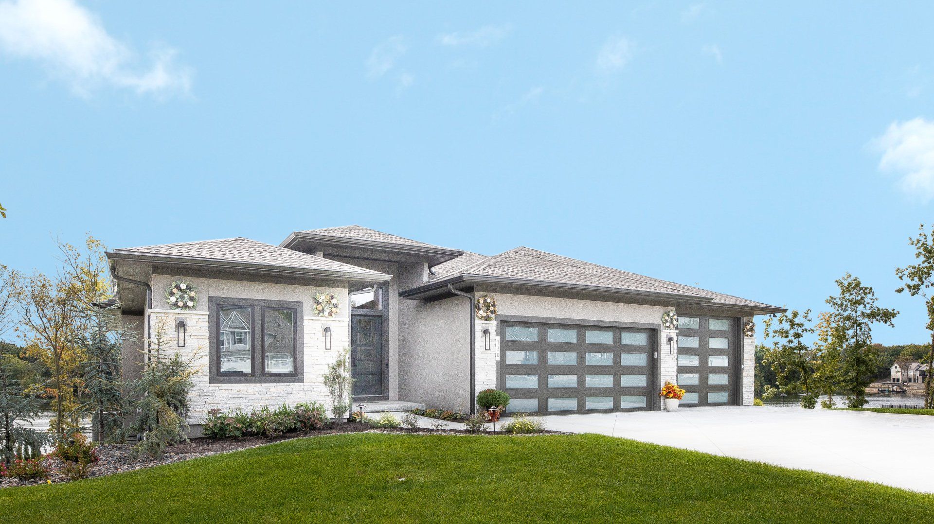A large white house with two garage doors is sitting on top of a lush green lawn.