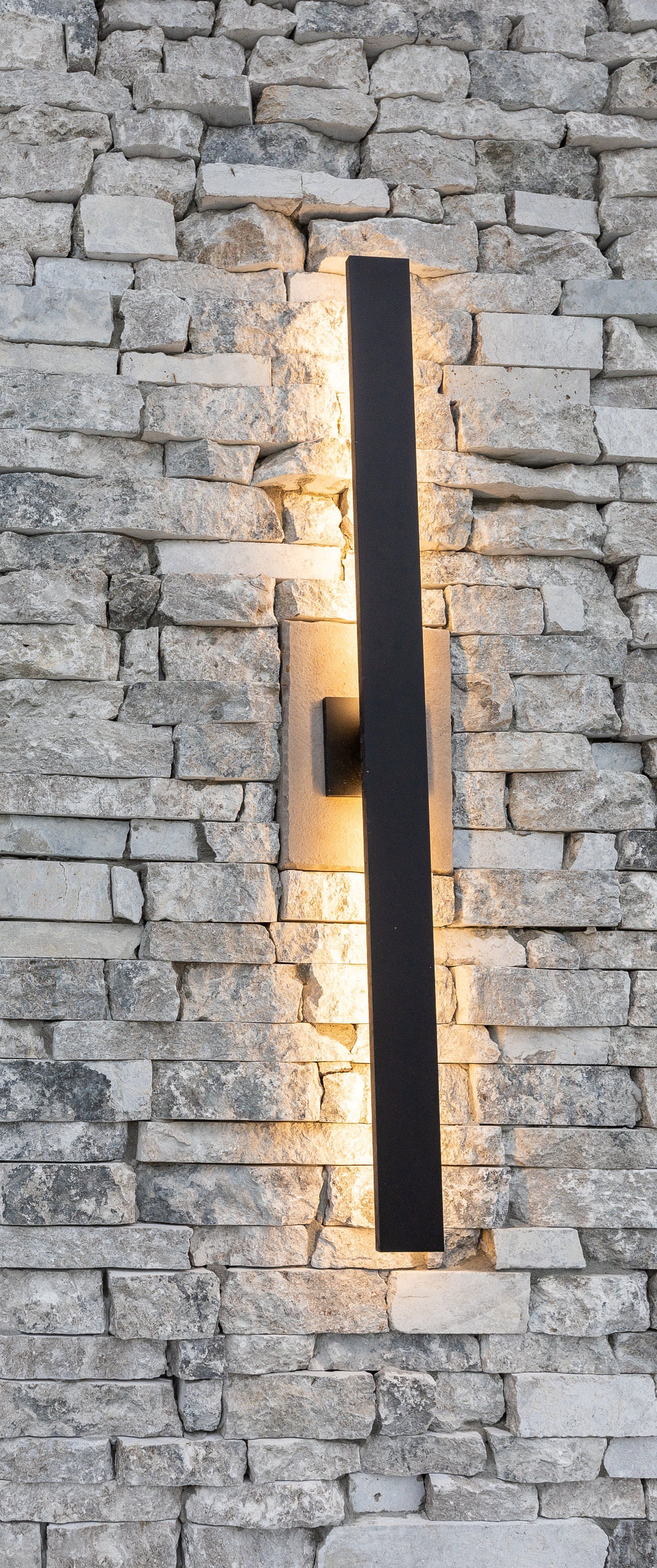 There is a light on the side of a brick wall.