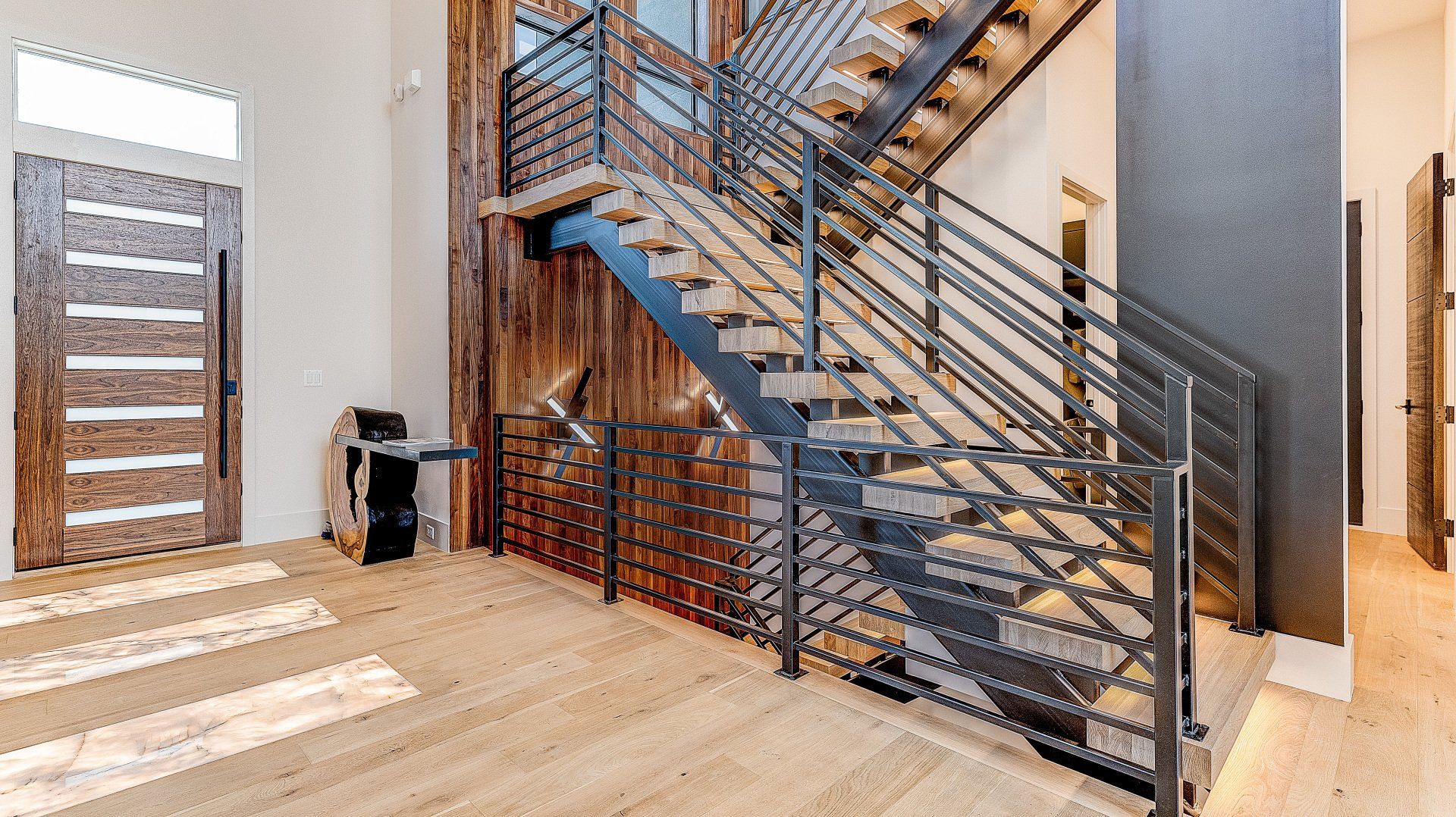 A modern staircase with a metal railing and wooden steps in a house.