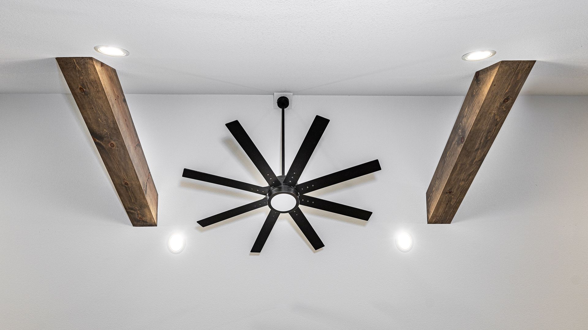 A ceiling fan is hanging from the ceiling in a room with wooden beams.