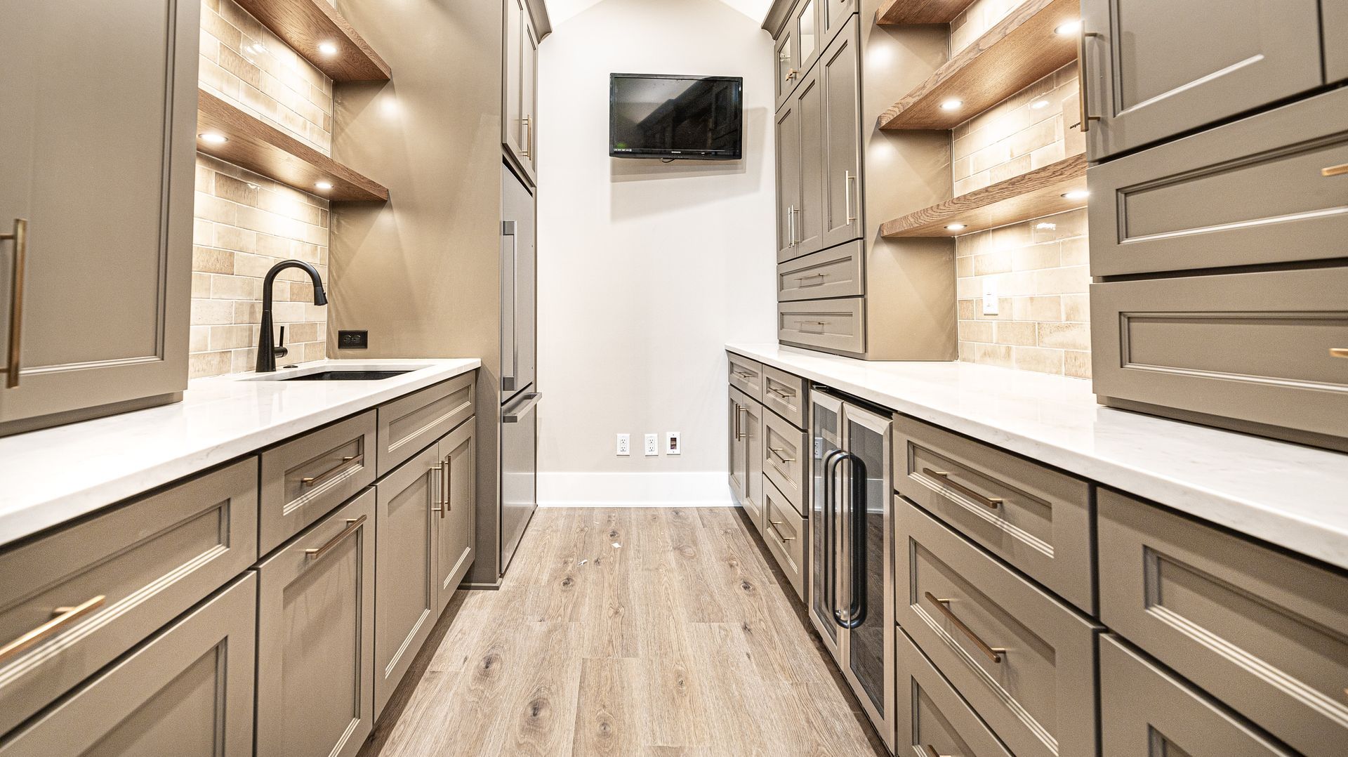 A kitchen with a lot of cabinets and a television on the wall.