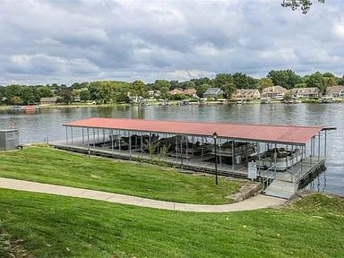 A dock with a red roof is sitting on the shore of a lake.