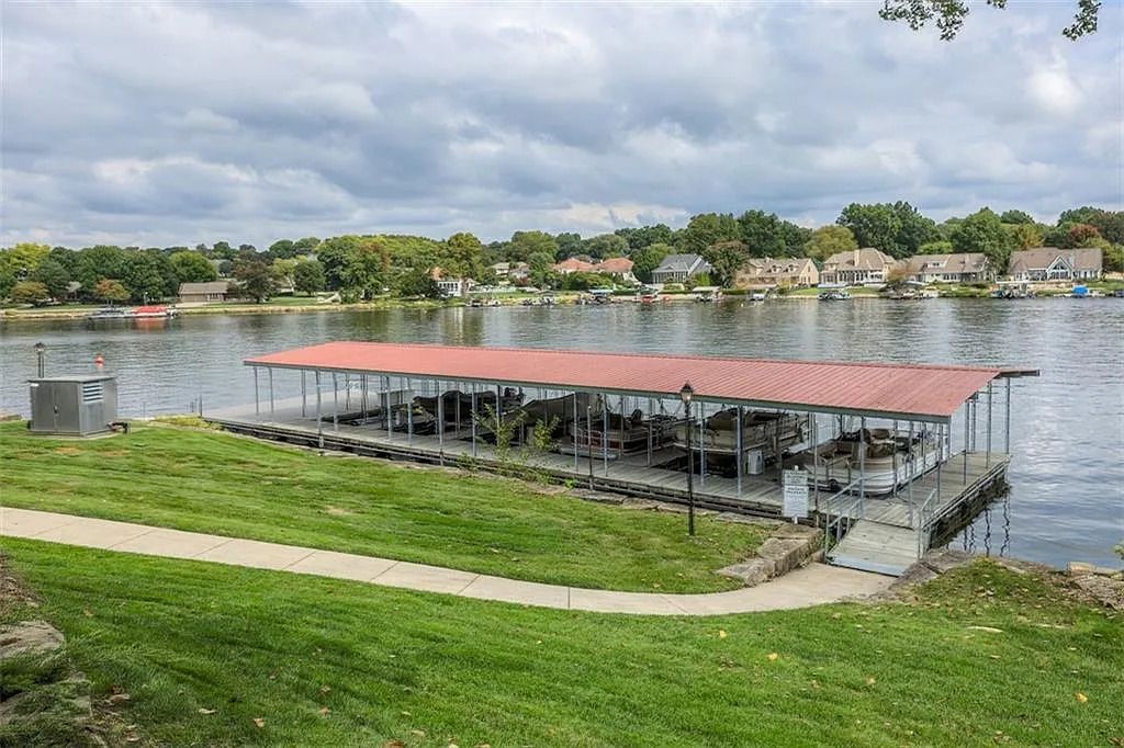 A dock with a red roof is sitting on the shore of a lake.