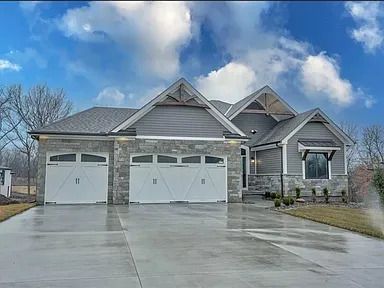 A large house with three garage doors and a concrete driveway.