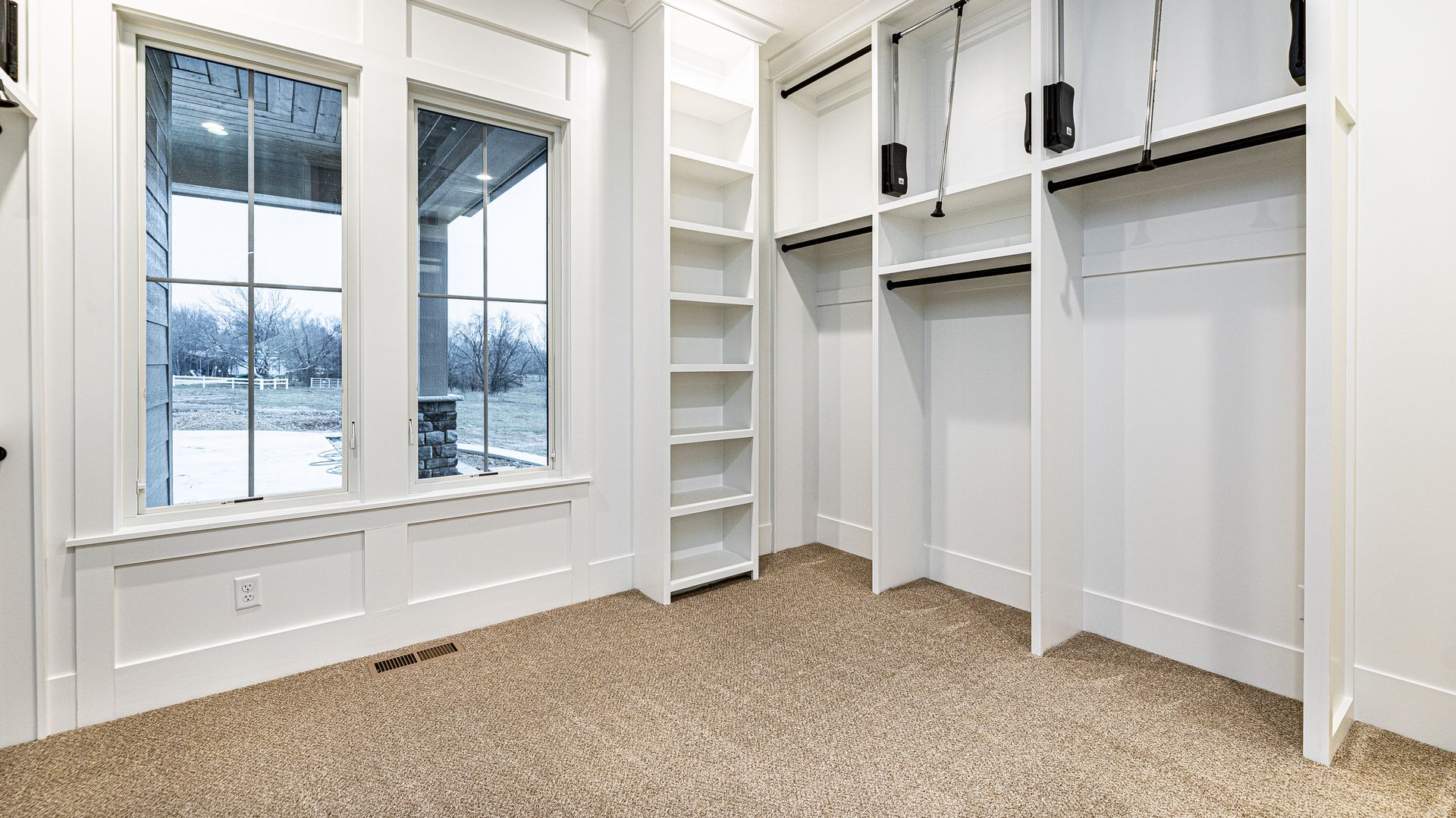 An empty walk in closet with lots of shelves and windows.