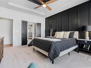 A bedroom with a king size bed and a ceiling fan.