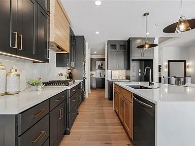 A kitchen with black cabinets , white counter tops , and wooden floors.