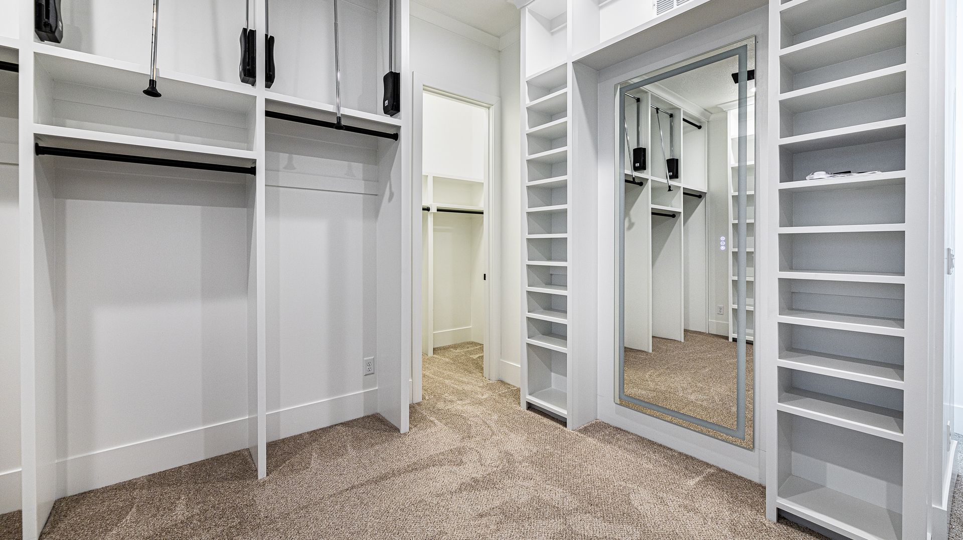 A walk in closet with lots of shelves and a large mirror.