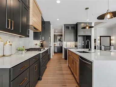 A kitchen with black cabinets , white counter tops , and wooden floors.