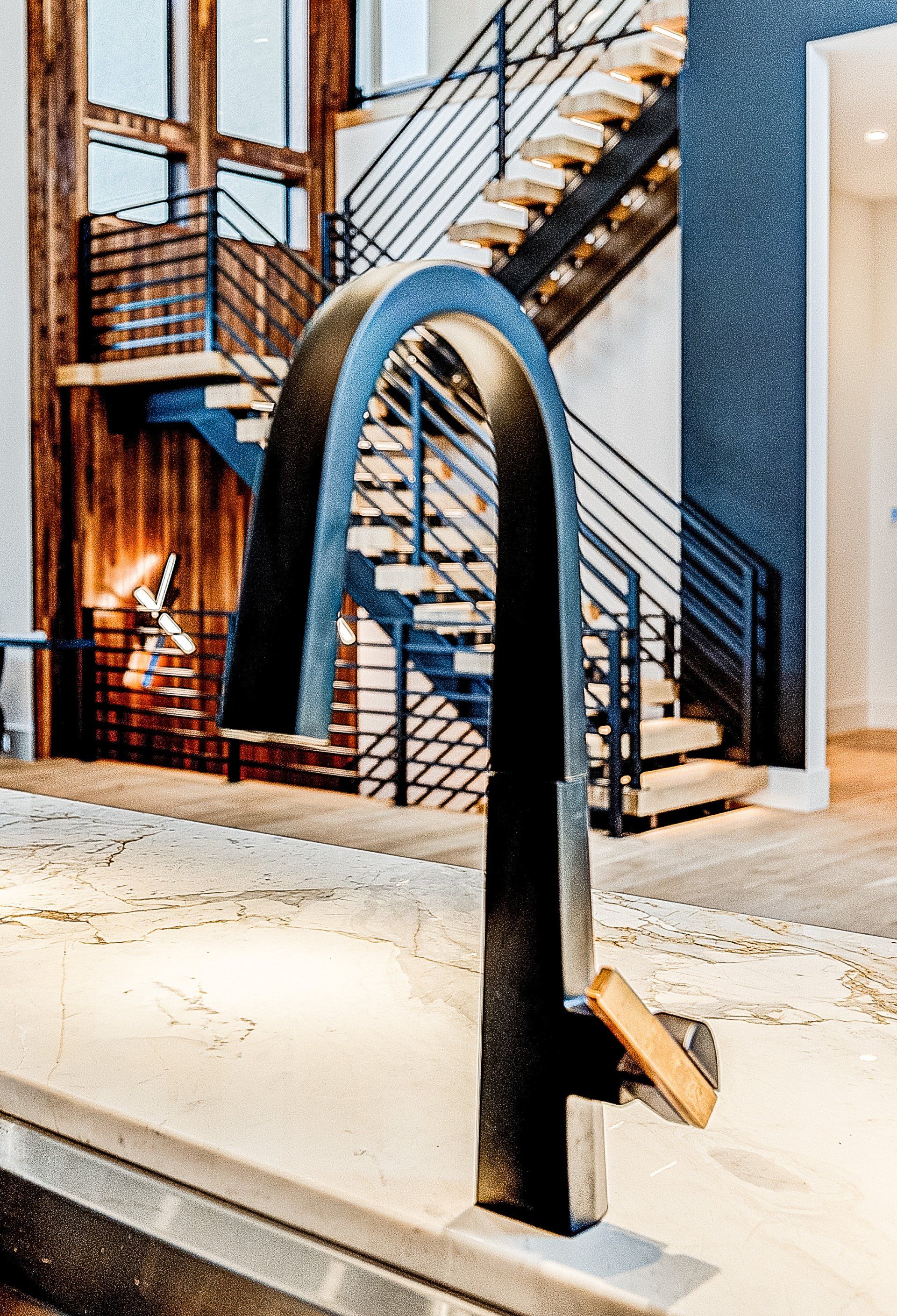 A kitchen sink with a faucet and stairs in the background