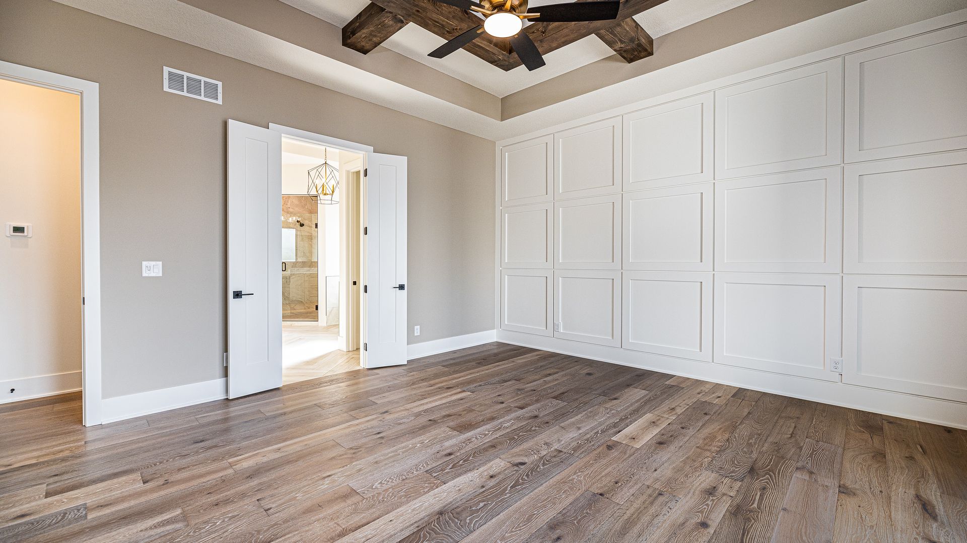 An empty bedroom with hardwood floors and a ceiling fan.
