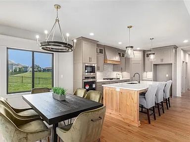 A dining room with a table and chairs and a kitchen with a large island.