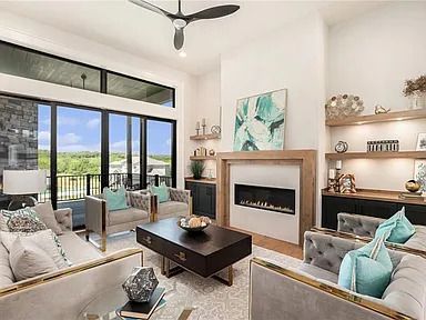 A living room with hardwood floors , a fireplace and a ceiling fan.