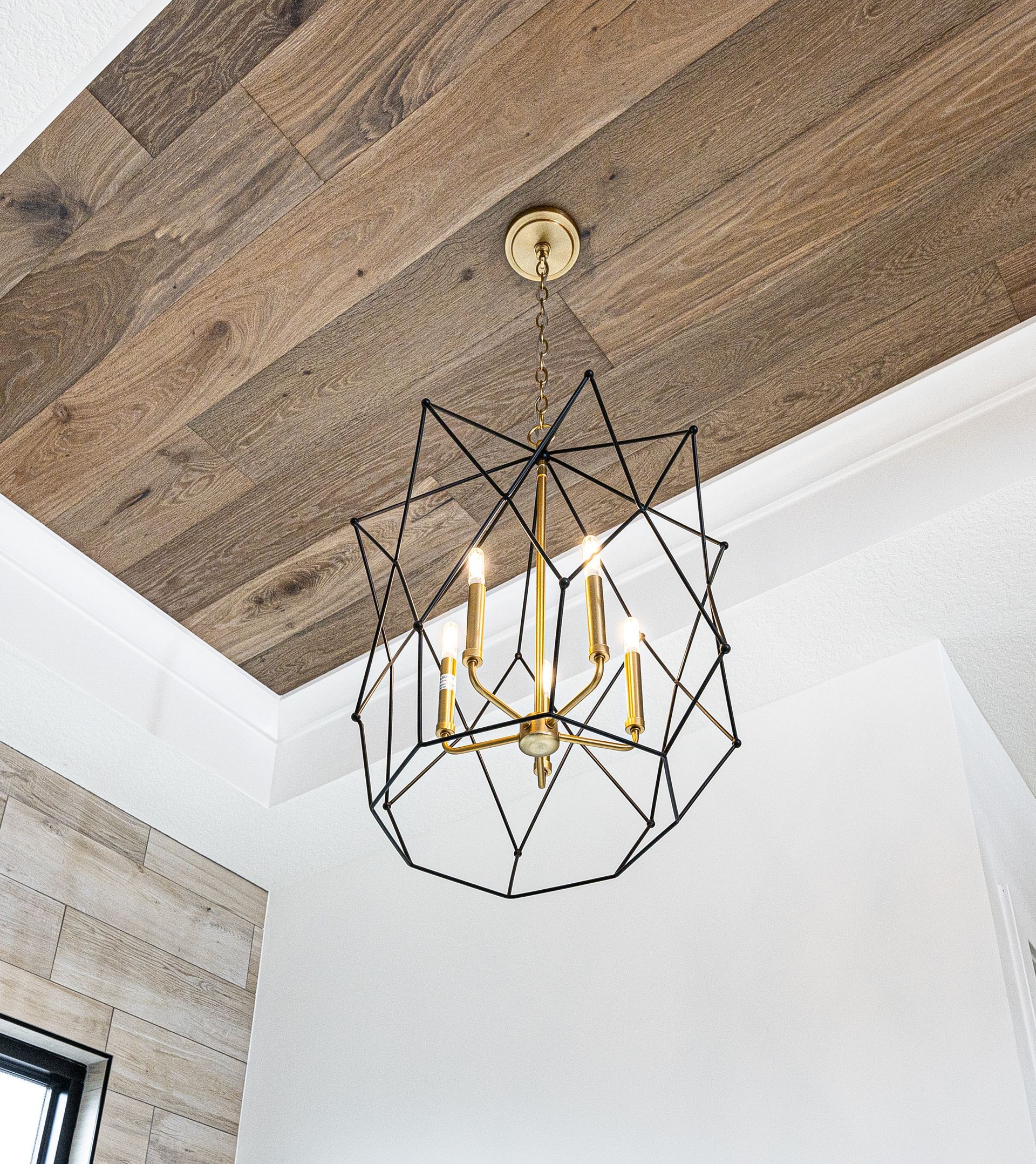 A chandelier is hanging from the ceiling of a room with a wooden ceiling.