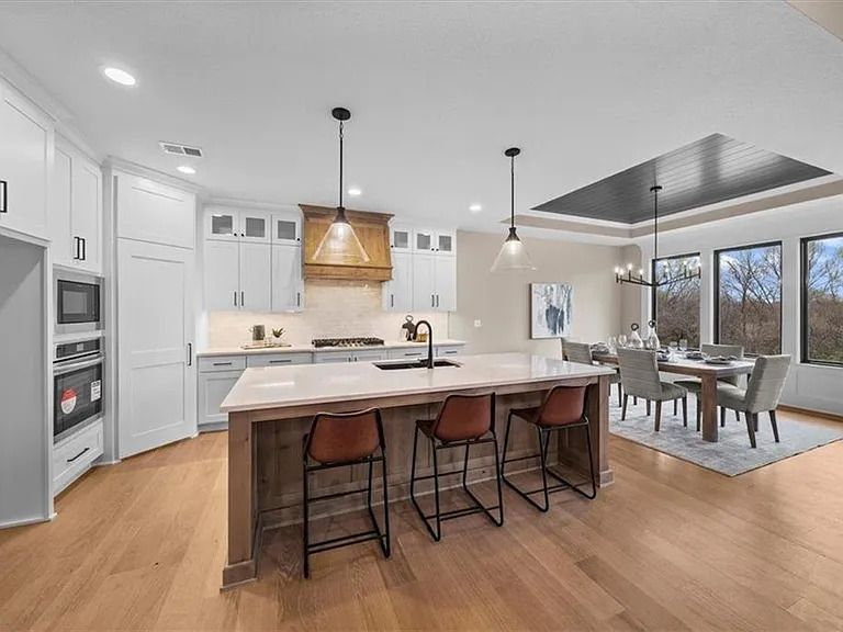 A kitchen with a large island in the middle and a dining room in the background.