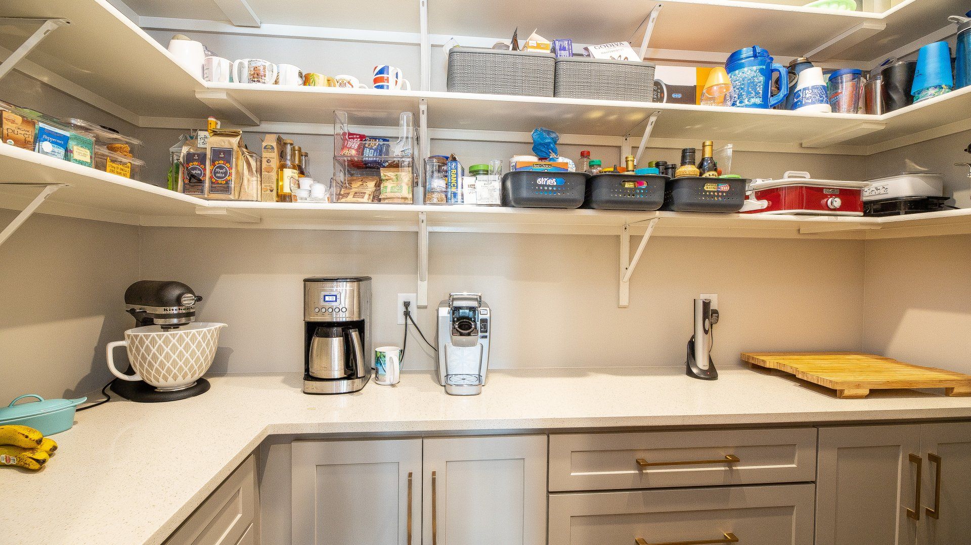 A kitchen with a coffee maker , mixer , and lots of shelves.