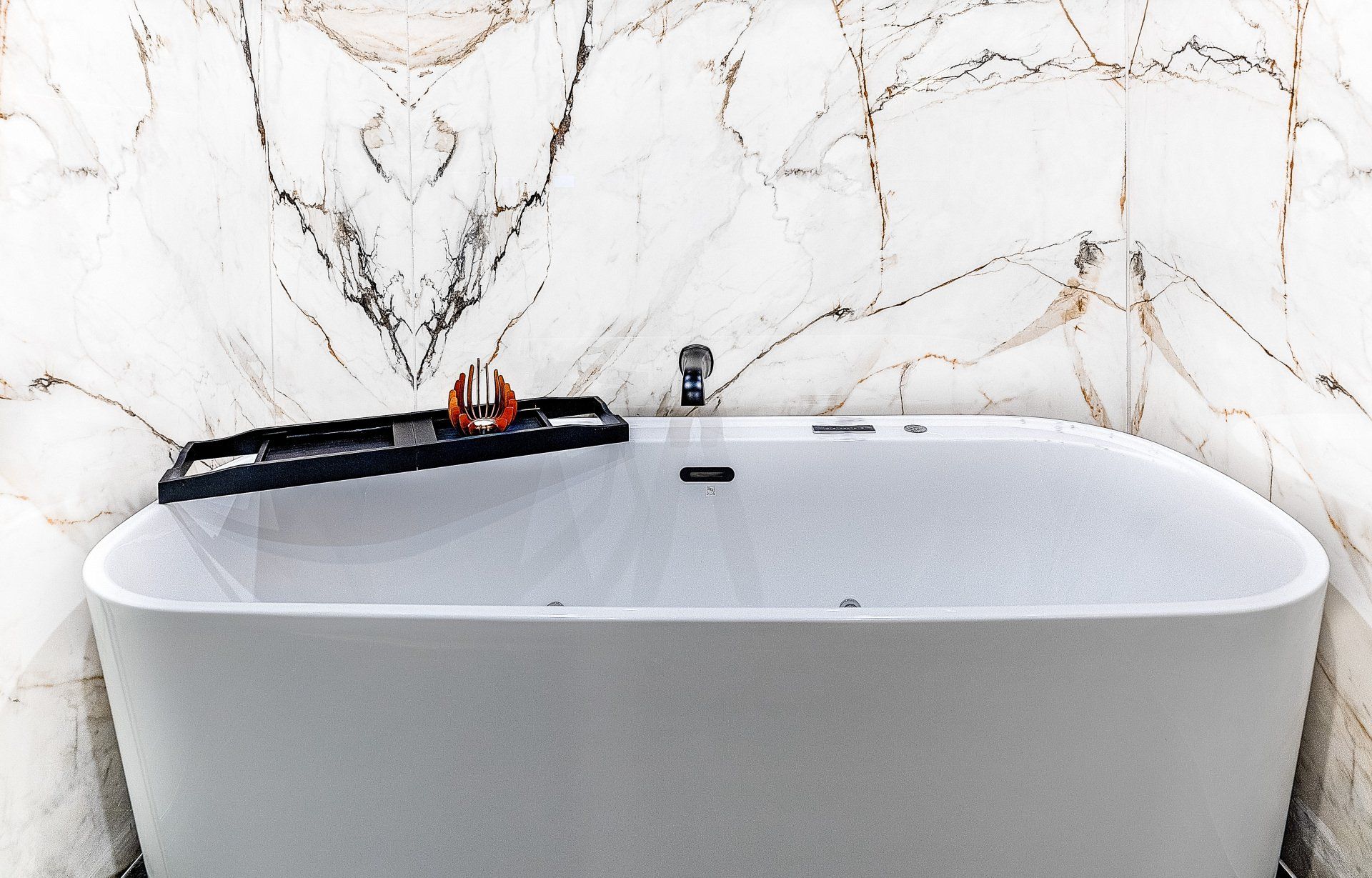 A white bathtub is sitting in a bathroom next to a marble wall.