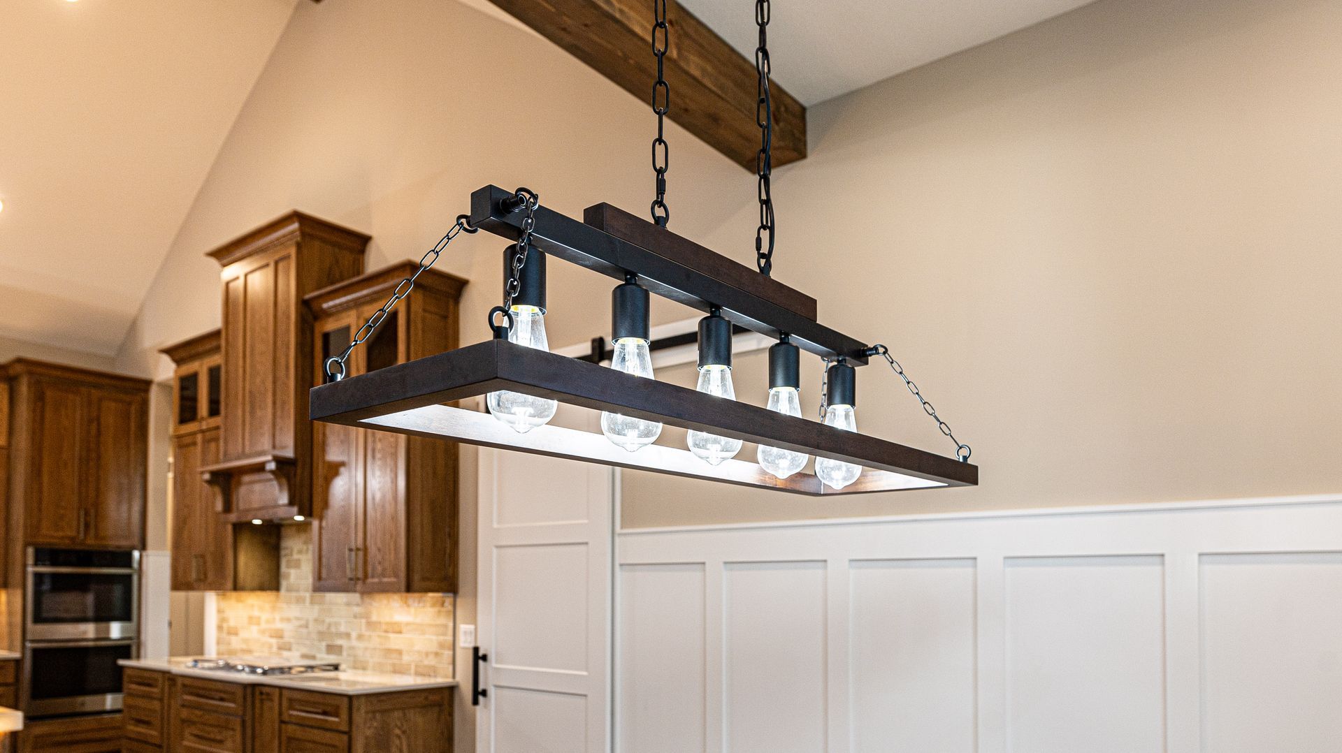 A wooden chandelier is hanging from the ceiling in a kitchen.