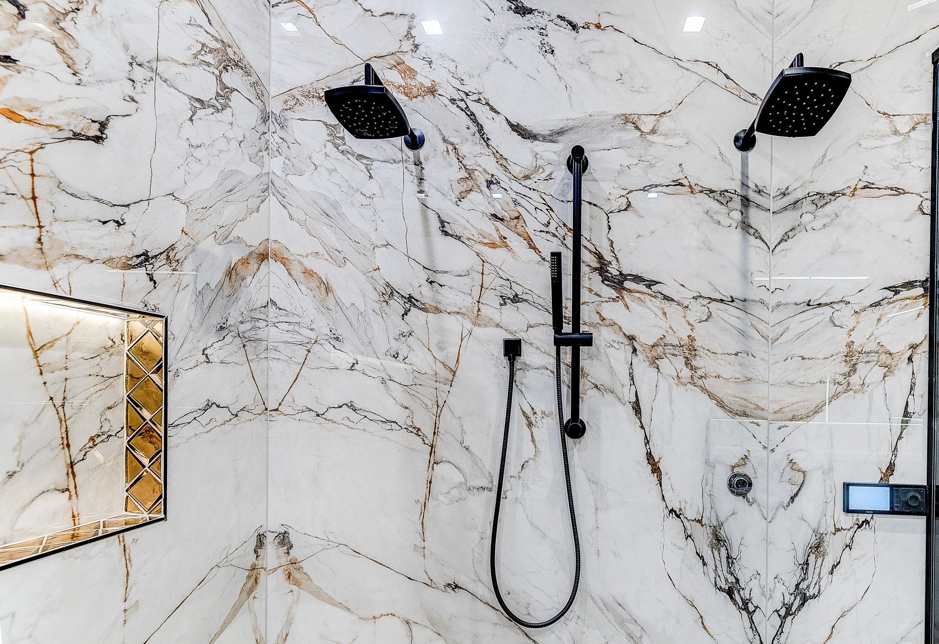 A bathroom with marble tiles and a double shower head.