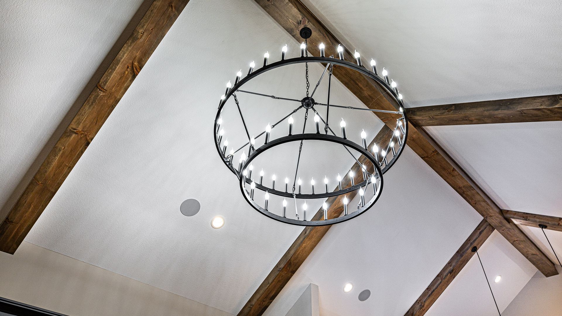 A chandelier is hanging from the ceiling of a room with wooden beams.