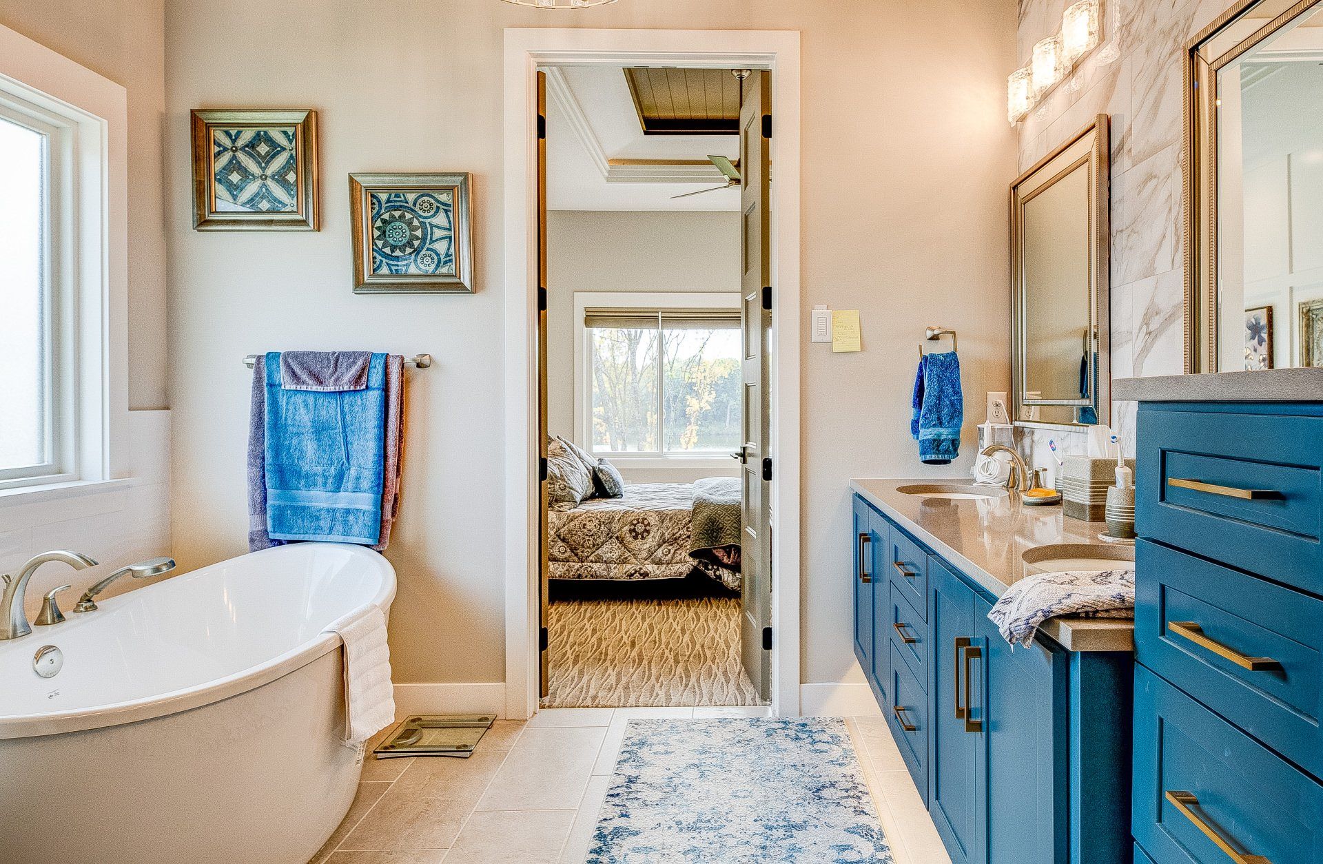 A bathroom with a bathtub , sinks , mirrors and blue cabinets.