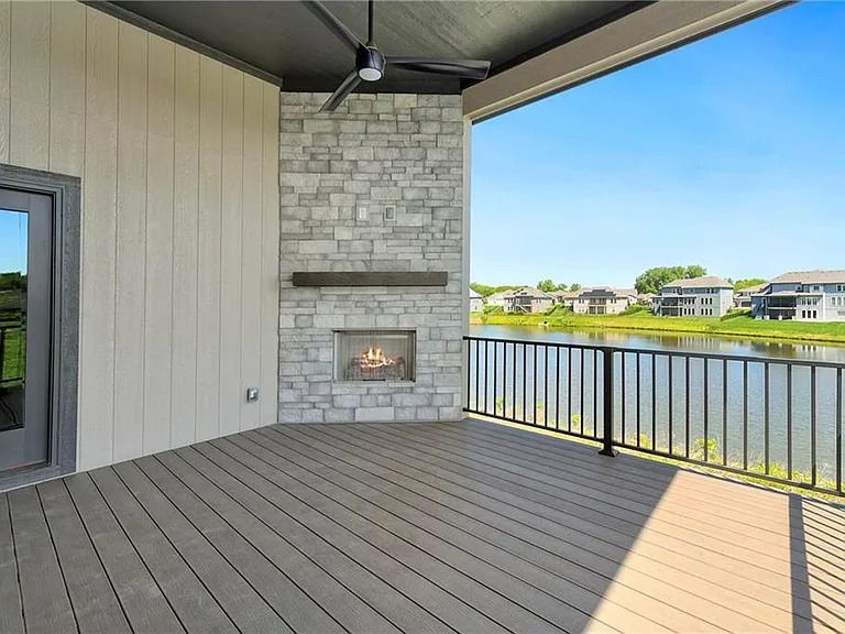 A deck with a fireplace and a view of a lake.
