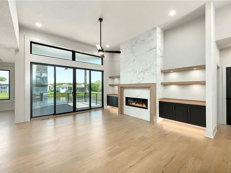 An empty living room with a fireplace and sliding glass doors.