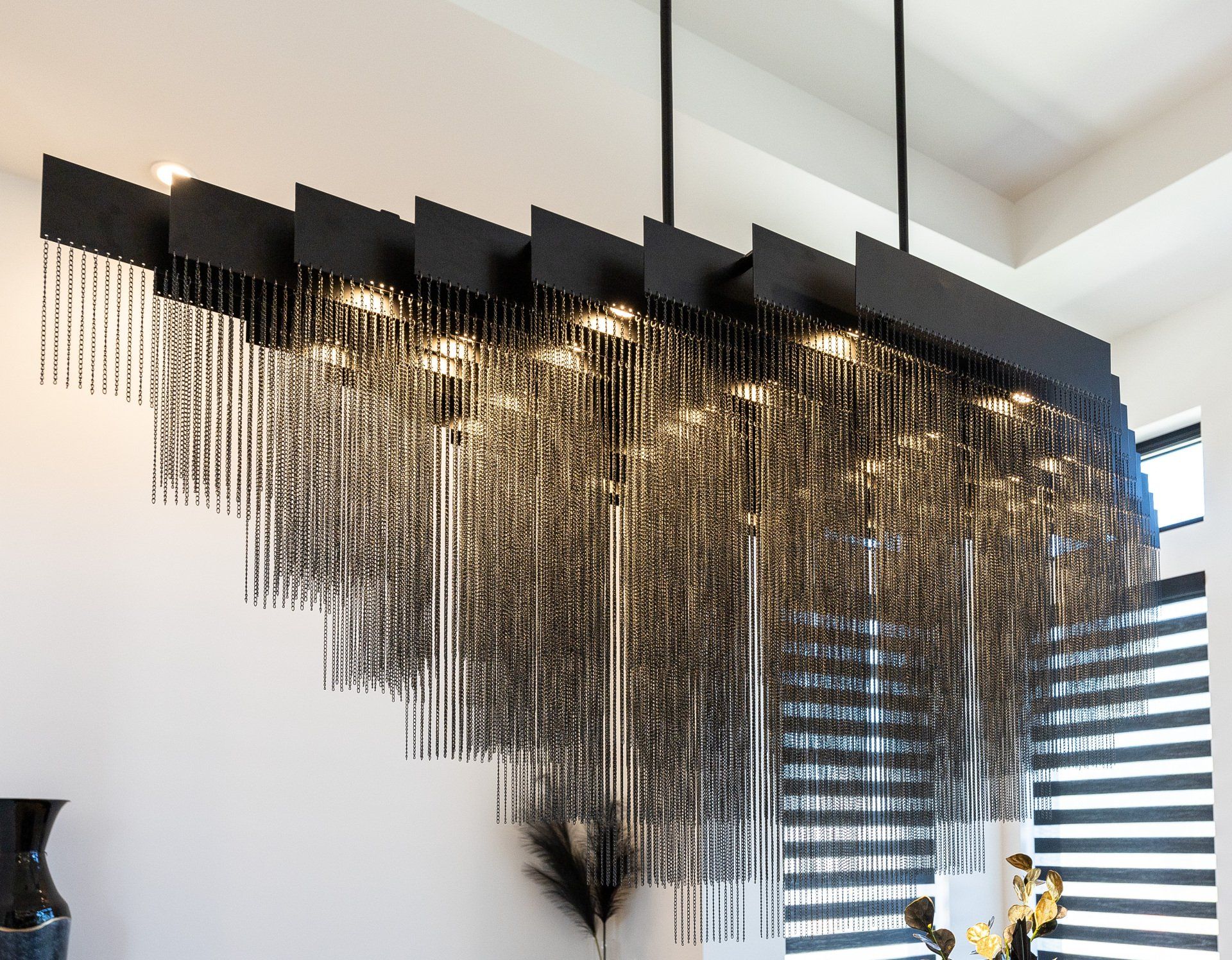 A long black chandelier is hanging from the ceiling in a room.
