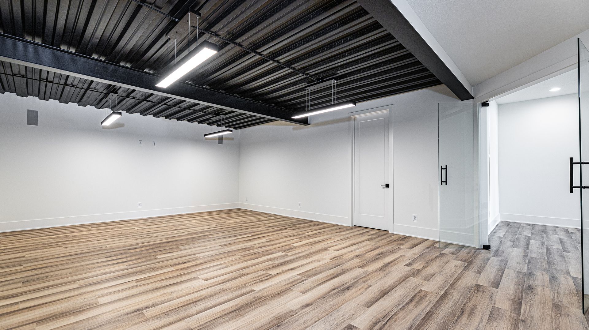 A large empty room with wooden floors and white walls.
