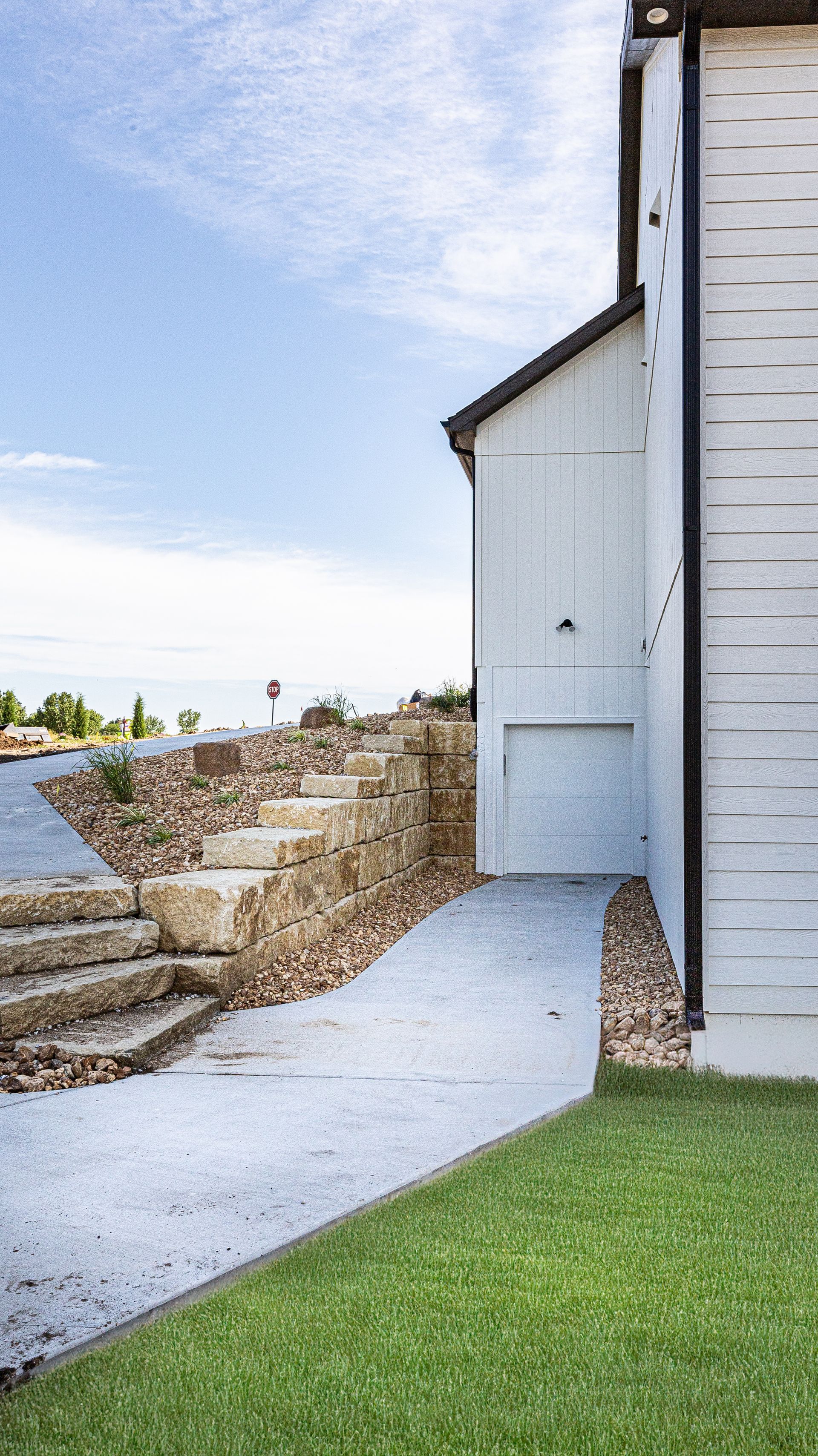 A white barn with stairs leading up to it and a ramp leading to it.