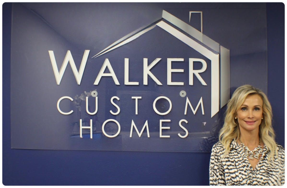 A woman stands in front of a walker custom homes sign