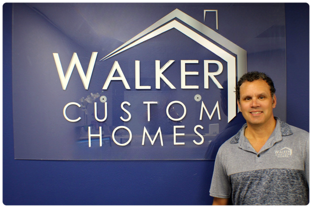 A man stands in front of a walker custom homes sign