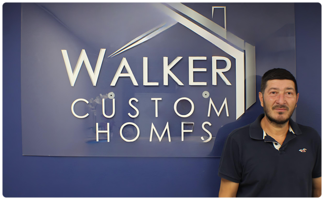 A man stands in front of a walker custom homes sign