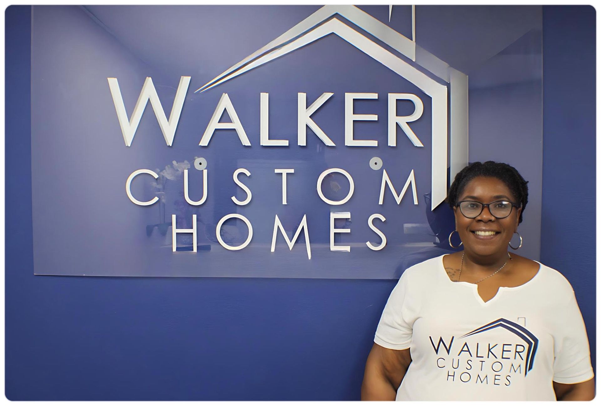 A woman is standing in front of a walker custom homes sign.
