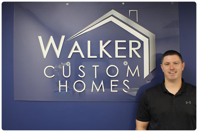 A man is standing in front of a walker custom homes sign