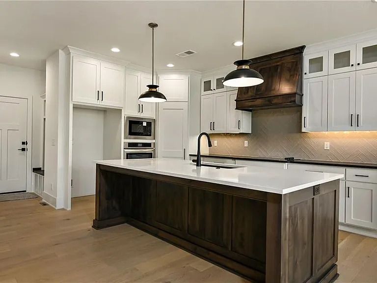A kitchen with white cabinets and a large island in the middle.
