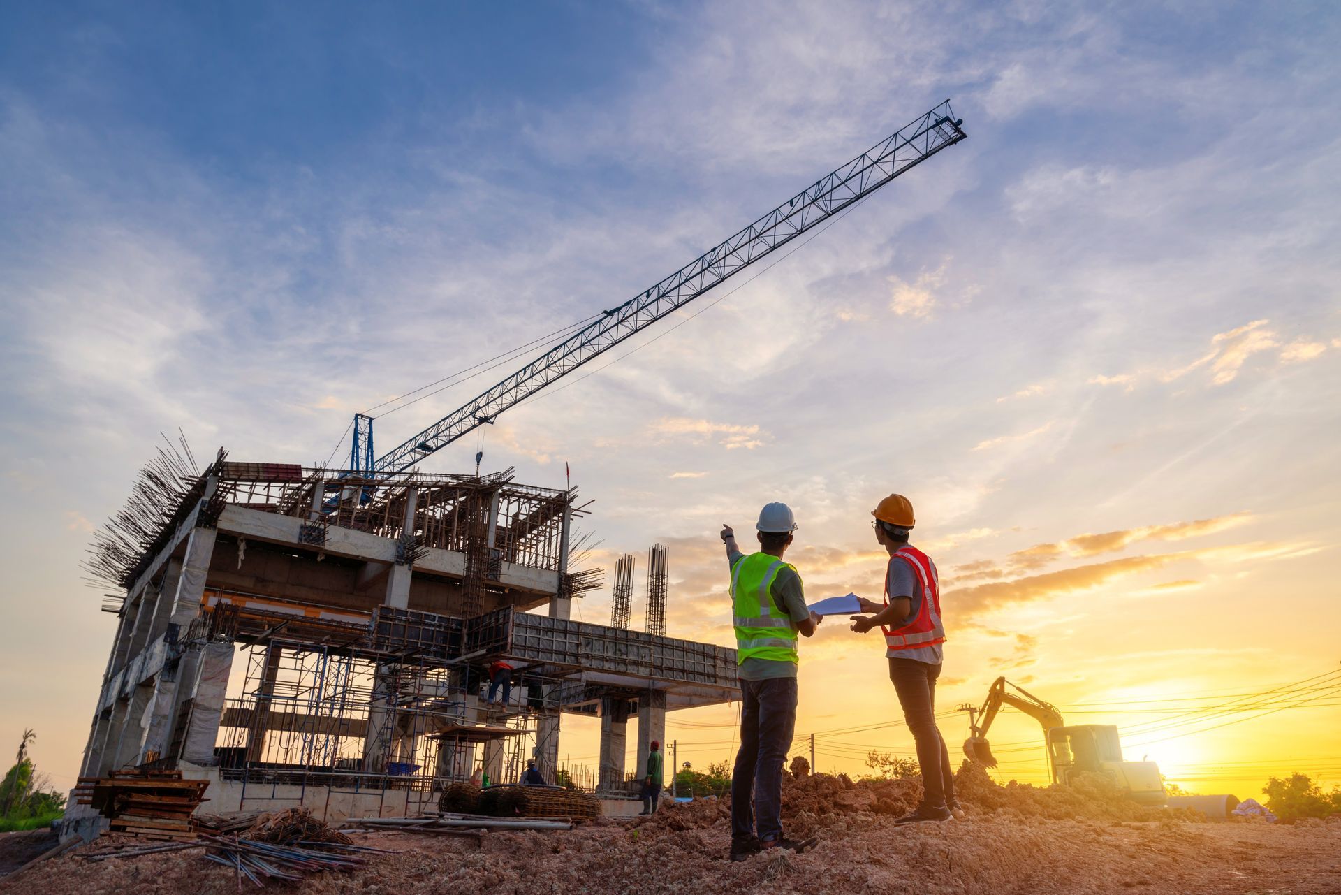 Construction workers at a building site, with a crane, pointing at a structure, sunset in the background.