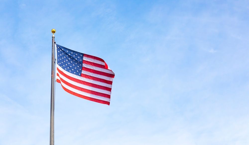American flag waving against a bright blue sky.