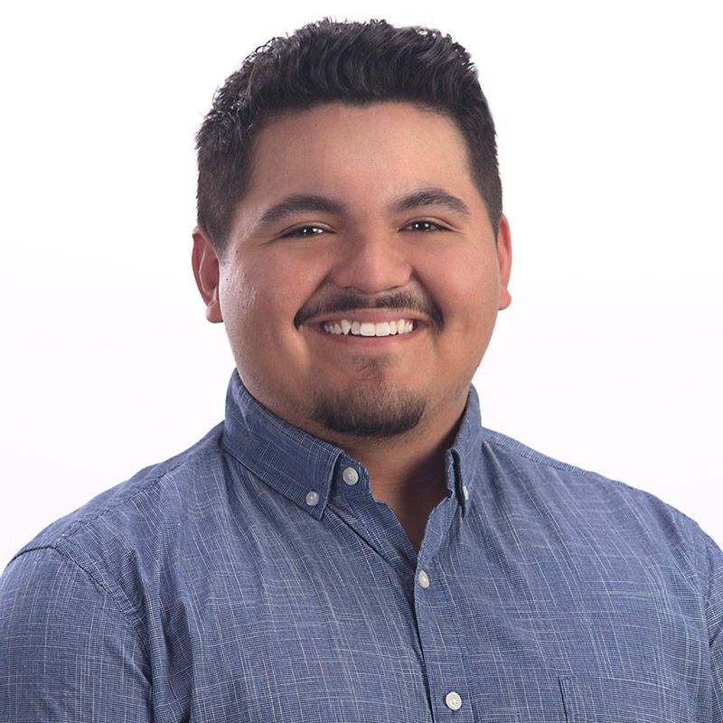 A man in a blue shirt is smiling for the camera.