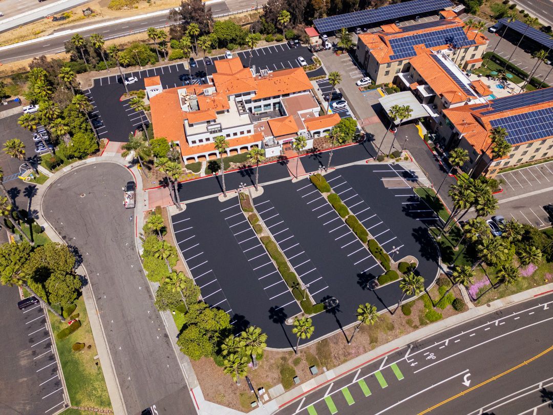 An aerial view of a parking lot with a building in the background.