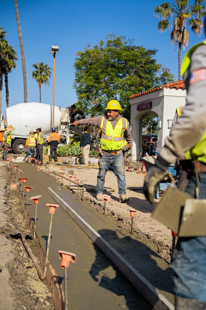A group of construction workers are working on a sidewalk.