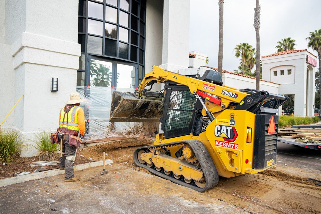 A construction worker is standing next to a yellow cat bulldozer.