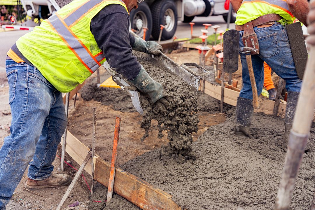 A group of construction workers are pouring concrete on a construction site.
